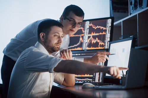 Dos hombres empleados viendo una pantalla y analizando datos